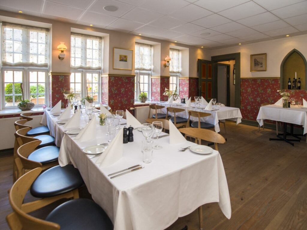 Elegant restaurant med dækkede borde og hvide servietter.