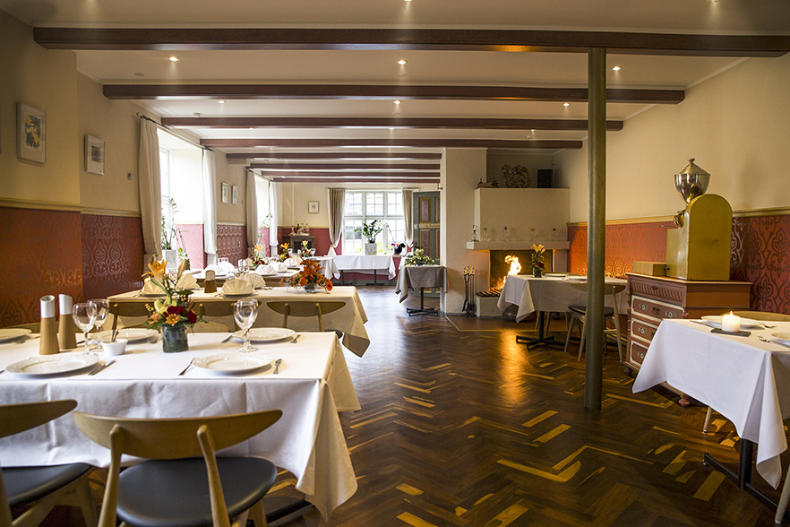Elegant restaurant med hvide duge og blomsterdekorationer.