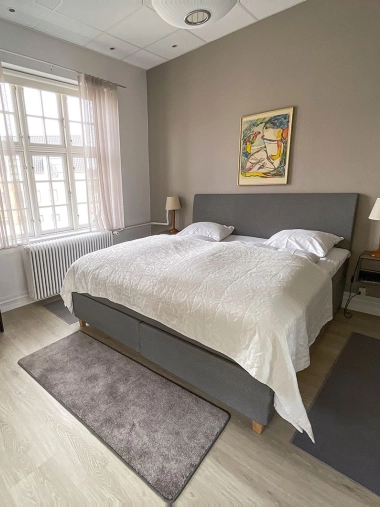 Moderne soveværelse med dobbeltseng og kunst på væggen.